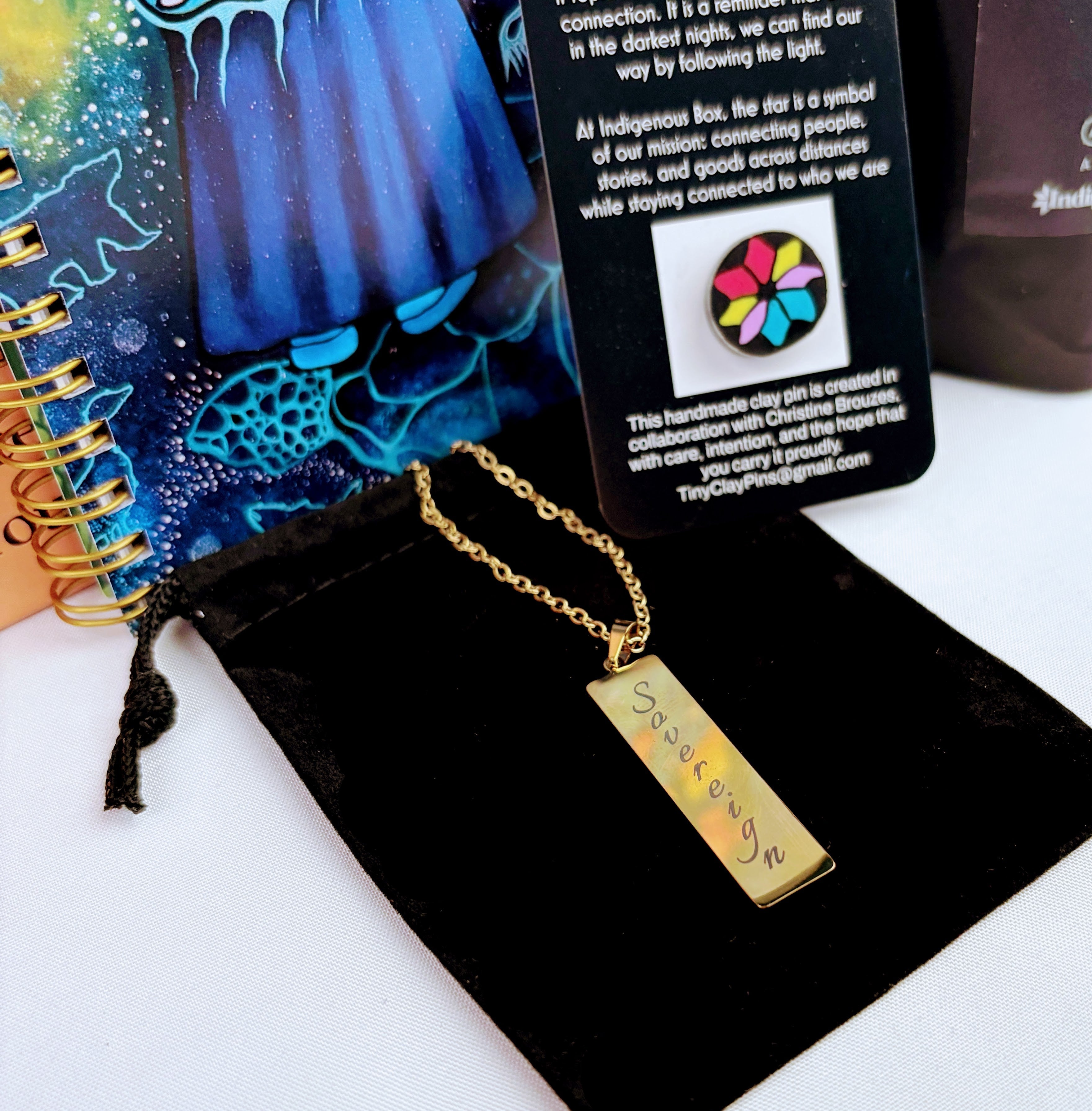 Gold pendant with engraved text on a black card with colorful design