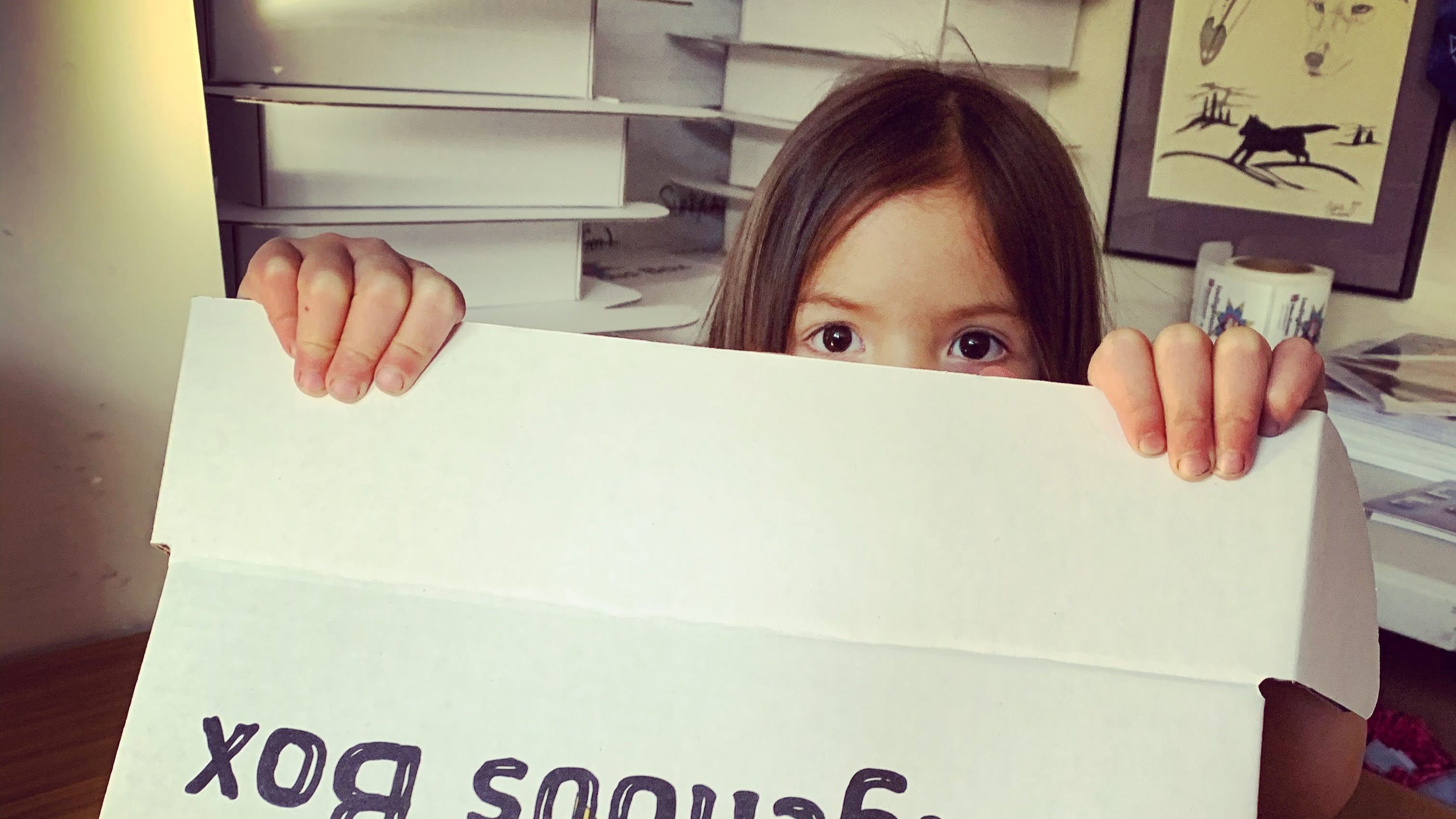 A child peeks over an open Indigenous Box lid
