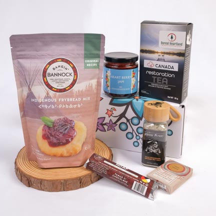 Assorted food products including a bag of Bannock, a box of tea, a jar of jam, and a package of chocolate on a white background.