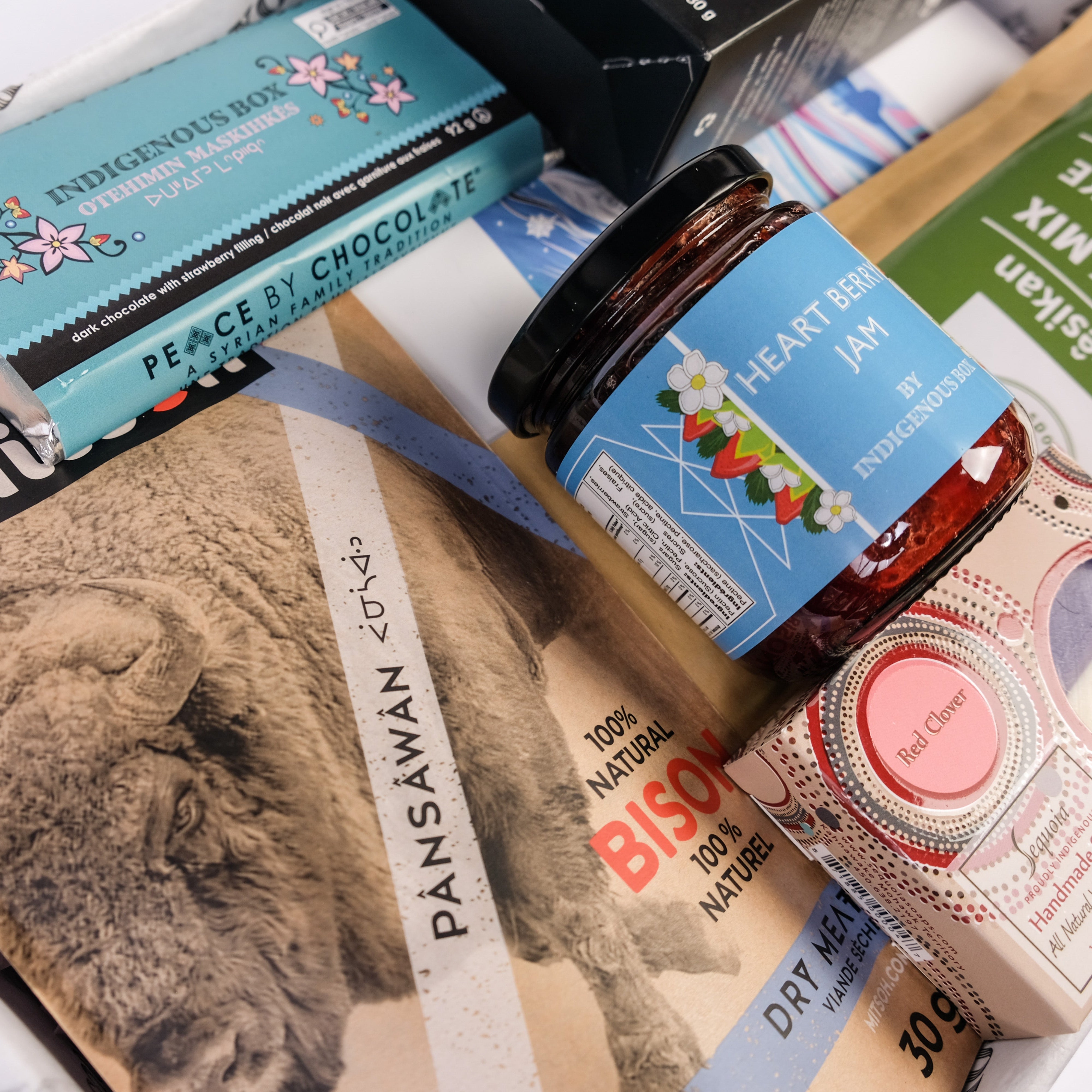 Assorted products including a jar of jam, a bottle of chocolate, and a box with a bear illustration on a white background.